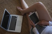 Sección baja de la mujer que usa tableta digital en casa - foto de stock