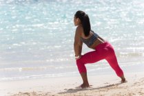 Mulher se exercitando na praia em um dia ensolarado — Fotografia de Stock