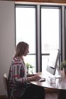 Жінка-виконавця, що працює на комп'ютері за столом в офісі — стокове фото