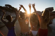 Grupo de amigos divirtiéndose en la playa al atardecer - foto de stock