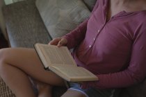 Donna che legge un libro in salotto a casa — Foto stock