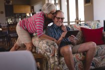 Senior couple using digital tablet in living room at home — Stock Photo