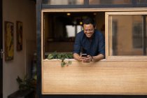 Усміхнений бізнесмен використовує мобільний телефон у кафе — стокове фото