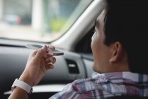 Крупный план человека, берущего мобильный телефон во время поездки на машине — стоковое фото