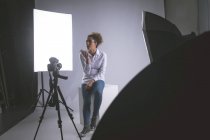 Жінка-фотограф розмовляє на мобільному телефоні в фотостудії — стокове фото