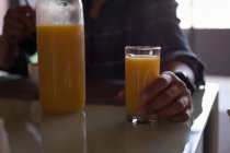 Средняя часть человека с апельсиновым соком дома — стоковое фото