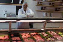 Butcher standing at counter in butcher shop — Stock Photo