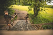 Homens aptos a treinar sobre o curso de obstáculos no campo de treinamento — Fotografia de Stock