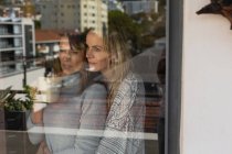 Lesbian couple embracing each other near window at home — Stock Photo