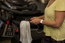 Donna disabile che utilizza il telefono cellulare durante l'esercizio su un tapis roulant — Foto stock