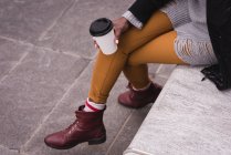 Low section of woman having coffee in city street — Stock Photo