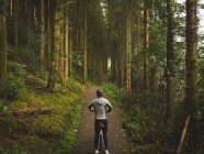 Rear view of cyclist on bicycle in lush forest — Stock Photo