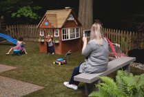 Mother taking photo of playing kids in the garden — Stock Photo