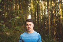 Junger Mann steht an einem sonnigen Tag im Wald — Stockfoto