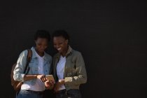Happy twins siblings using mobile phone in city street — Stock Photo