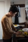 Jovem cortando legumes na cozinha — Fotografia de Stock