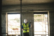 Engineer with level gauge using his phone at the construction site — Stock Photo