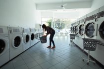 Junge Frau benutzt Waschmaschine am Waschsalon — Stockfoto