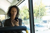 Frau benutzt Handy während Busfahrt — Stockfoto