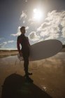 Surfista con tabla de surf en la playa en un día soleado - foto de stock