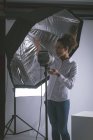 Женщина-фотограф регулирует стробоскопы в фотостудии — стоковое фото