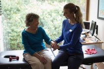 Fisioterapista che fa un massaggio alle mani a una donna anziana sorridente — Foto stock