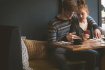 Casal jovem usando telefones celulares no café — Fotografia de Stock