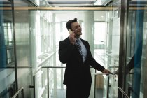 Улыбающийся бизнесмен разговаривает по телефону в лифте — стоковое фото
