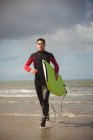 Surfista determinado com prancha correndo na praia — Fotografia de Stock
