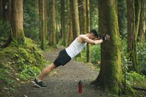 Вмістити чоловіка робити вправи для розтягування в лісі — стокове фото