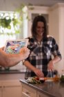 Personne photographiant femme pendant la cuisson des aliments dans la cuisine — Photo de stock