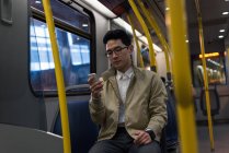Jovem usando telefone celular enquanto viaja no trem — Fotografia de Stock