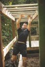 Fit man grimpant barres de singe au camp d'entraînement — Photo de stock
