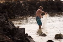 Pescatore che tiene la rete da pesca sulla spiaggia — Foto stock