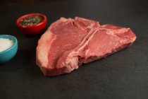Primer plano de la carne con especies sobre fondo de hormigón - foto de stock