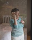 Mujer mayor hablando en un teléfono móvil en casa - foto de stock