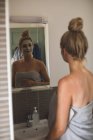 Беременная женщина смотрит на зеркало в ванной комнате дома — стоковое фото
