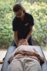 Fisioterapista che fa un massaggio alla testa alla donna anziana a casa — Foto stock