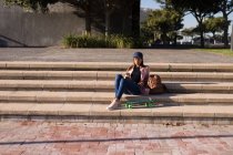 Donna seduta sui gradini e con il cellulare nel parco — Foto stock