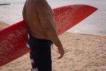 Sección media del surfista masculino sosteniendo la tabla de surf - foto de stock