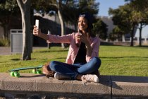 Женщина делает селфи во время выпивки в парке — стоковое фото