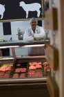 Butcher standing at counter in butcher shop — Stock Photo