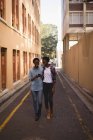 Twins siblings using mobile phone while walking in the street on a sunny day — Stock Photo