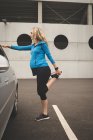 Pregnant woman exercising on a car at parking area — Stock Photo