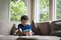 Niño usando tableta digital en la sala de estar en casa - foto de stock