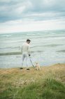 Вид сзади человека с собакой, стоящей на берегу моря — стоковое фото