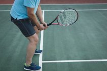 Низкая часть пожилого человека играет в теннис на теннисном корте — стоковое фото