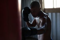 Jovem boxeador masculino praticando boxe no estúdio de fitness — Fotografia de Stock