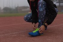 Жінка-спортсменка зав'язує шнурки на біговій доріжці — стокове фото