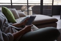 Sección media de la mujer que usa el ordenador portátil en la sala de estar en casa - foto de stock